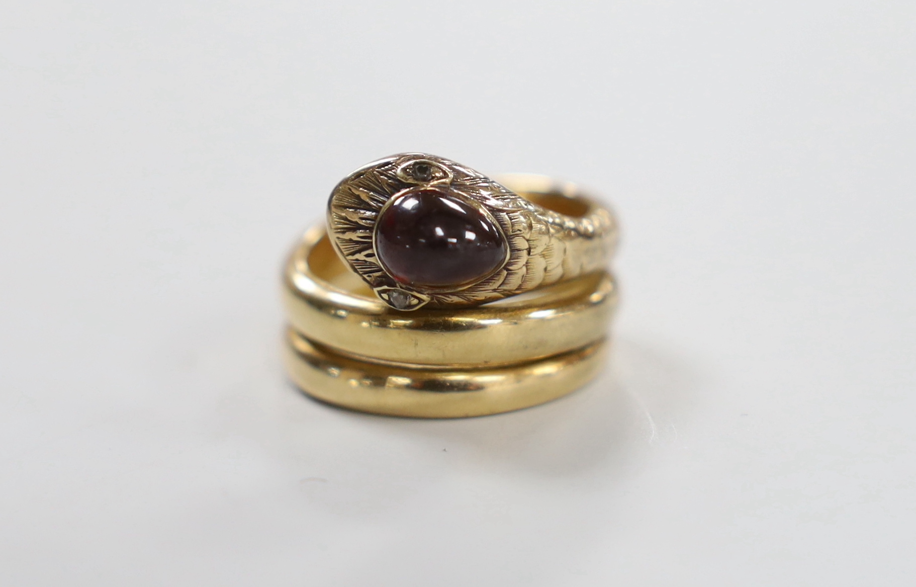 A yellow metal and garnet set coiled serpent ring, with diamond chip eyes, size P, gross weight 15 grams.